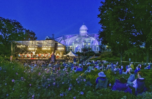 Promusica Chamber Orchestra performs at Franklin Park, The Palm House at the Franklin Park Conservatory is illuminated by artist James Turrell's Light Raiment ll in the background, Columbus Ohio